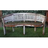 A teak framed semi-elliptic garden bench with slatted back and seat, on block supports,