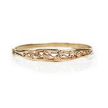 A 9ct two colour gold Welsh oval hinged bangle, pierced with foliate decoration,