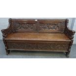 Edwards and Roberts; a carved oak box seat settle, with beast arm finials, 142cm wide x 78cm high.