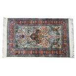 An Indian silk rug, the indigo field with a vase rising to two flying birds, floral sprays,