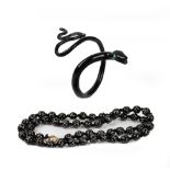 A black coral bead necklace, formed of fifty three beads inlaid with white metal pins,