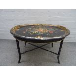 A Victorian polychrome floral painted oval papier mache tray on a later faux bamboo stand,