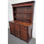 A George III oak dresser, the enclosed two tier plate rack, over six drawers and pair of cupboards,