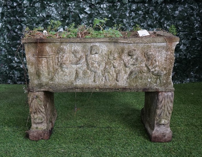A reconstituted stone rectangular planter relief cast with cherubs resting on a pair of scroll