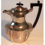 A silver hot water jug of panelled oval form, having black fittings, Sheffield 1924,