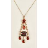 A gold, foil backed flat cut garnet and seed pearl set pendant,
