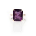 A gold ring, claw set with a cut cornered rectangular step cut amethyst, detailed indistinctly 14 K,