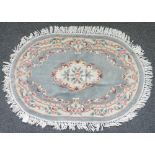 An oval hooked Chinese rug, sage floral field, 184cm x 123cm and a similar smaller, 150cm x 90cm.