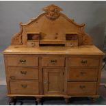 An early 20th century pine dresser base with nine drawers over a cupboard base, on turned supports,