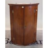 A George III mahogany bowfront hanging corner cupboard, 68cm wide x 97cm high.