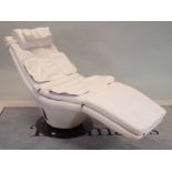 A modern reclining/massage low armchair with faux white leather on circular revolving metal base,