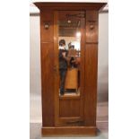 An early 20th century oak Art Nouveau single wardrobe with central mirrored door on plinth base,