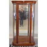 A modern fruitwood floor standing display cabinet with glass front, on plinth base,