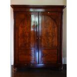 A Biedermeier mahogany armoire, the moulded cornice above a pair of arched panel doors,