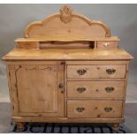 An early 20th century pine side chest with a cupboard door flanked by three short drawers on turned