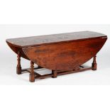 A 17th century style oak low gateleg table, with hinged oval top and two end drawers,