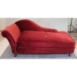 A modern hardwood framed chaise longue with red upholstery on tapering supports,