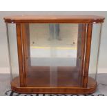 A modern fruitwood display cabinet with glass front and rounded ends, on plinth base,