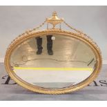 An Adams style giltwood oval wall mirror with urn and ribbon crest with bevelled glass,