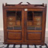 An Edwardian oak hanging wall cupboard with a central drawer flanked by two short drawers,