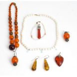 A pair of reconstituted amber drop shaped pendant earrings, a reconstituted amber heart shaped...