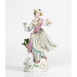 A Meissen figure of a shepherdess, circa 1770, modelled standing before a tree stump in...