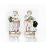A pair of Meissen figures of children standing beside columns, late 19th century, the boy...