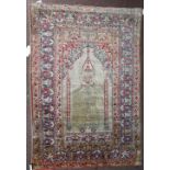 An antique silk Turkish prayer rug, the light brown mehrab with a pair of columns rising to a...