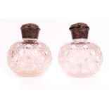 A pair of Victorian silver mounted spherical cut glass scent bottles, the hinged caps embossed...