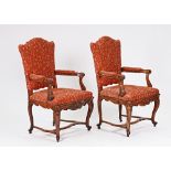 A pair of French 19th century walnut fauteuils with shaped backs and open arms on carved...
