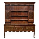 An 18th century inlaid oak dresser, the enclosed three tier plate rack with cupboards over...
