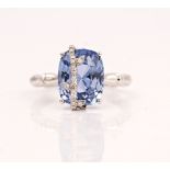 A white gold, sapphire and diamond ring, claw set with the cushion shaped sapphire with an...