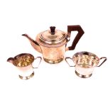 A silver three piece tea set, comprising; a teapot, with brown composition fittings, a twin...
