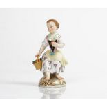 A Meissen figure of a girl, late 19th/early 20th century, modelled seated holding a basket of...