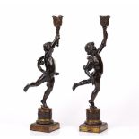 A pair of continental patinated bronze figural candlesticks