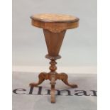 A Victorian walnut sewing table with tapering column on three downswept supports