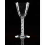 An opaque twist wine glass, circa 1920s, in 18th century style, the rounded funnel bowl raised...