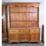 A late Victorian pine kitchen dresser with a two tier plate rack over three short drawers on...