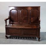 An 18th Century oak settle with panelled back over lift top seat