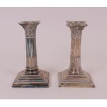 A pair of silver candlesticks, each designed as a Corinthian column, raised on a stepped...
