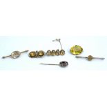 A gold brooch, collet set with a row of four oval cut citrines, a citrine two stone brooch,...