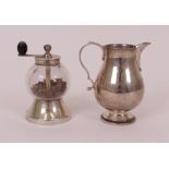 A silver cream jug and a pepper mill