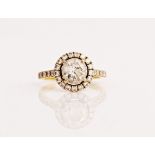 A gold and diamond ring, claw set with the principal circular cut diamond within a halo...