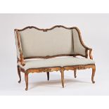 An 18th century French high wingback carved walnut framed sofa on scroll supports, 143cm wide...