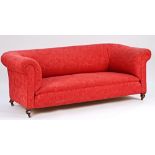 A late Victorian red upholstered Chesterfield style sofa on turned feet.