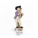 A Meissen figure of a boy playing the bagpipes, 19th century, standing wearing a black tricorn...