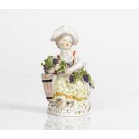 A Meissen figure of a girl vintner, 20th century, modelled seated beside a grape hod carrying...