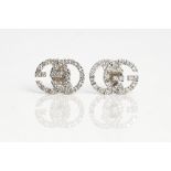 A Gucci pair of white gold and diamond earstuds, each designed as GG, mounted with circular...