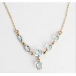 A gold and aquamarine necklace, the front collet set with a row of five graduated oval cut...