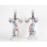 A pair of German porcelain four-light candelabra, early 20th century, modelled as a seated...